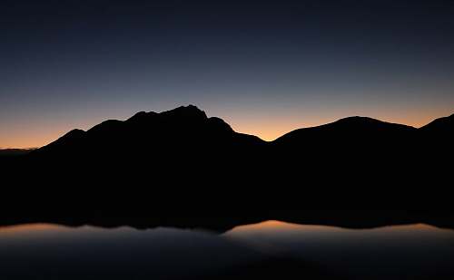 desktop wallpapers silhouette photography of mountain near body of water desktop backgrounds